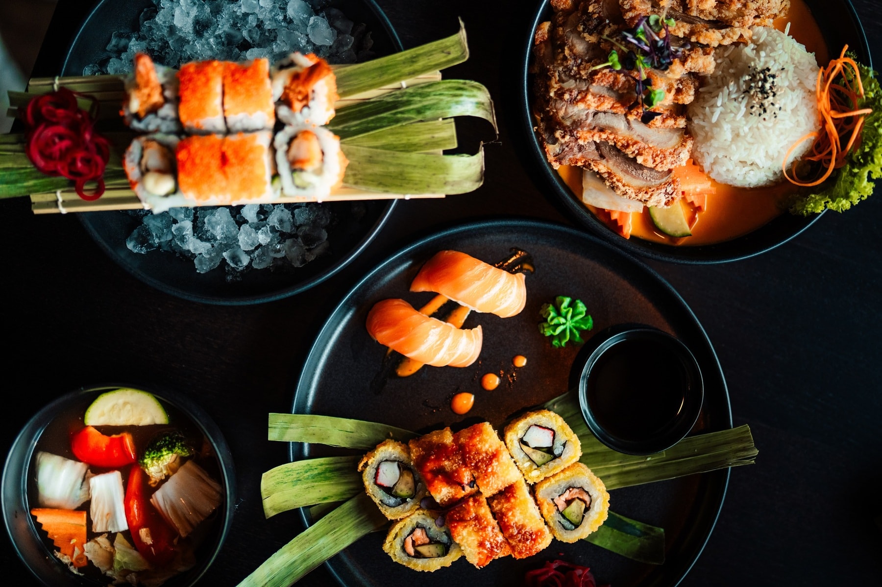 Japanischer Esstisch mit Lachs-Sushi, frittiertem Sushi, knusprigem Hähnchen mit Reis und eingelegtem Gemüse.